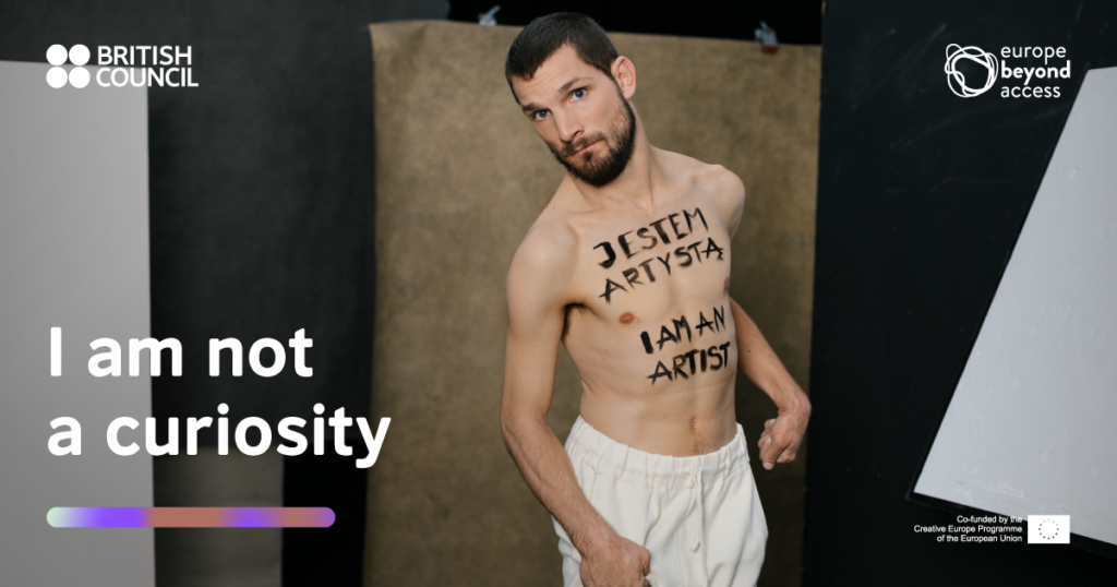 A male performer with Cerebral Palsy has 'I am an artist' written on his chest.
