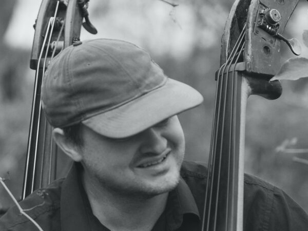 Richard Andersson close up with his double bass and a double bass in the background 