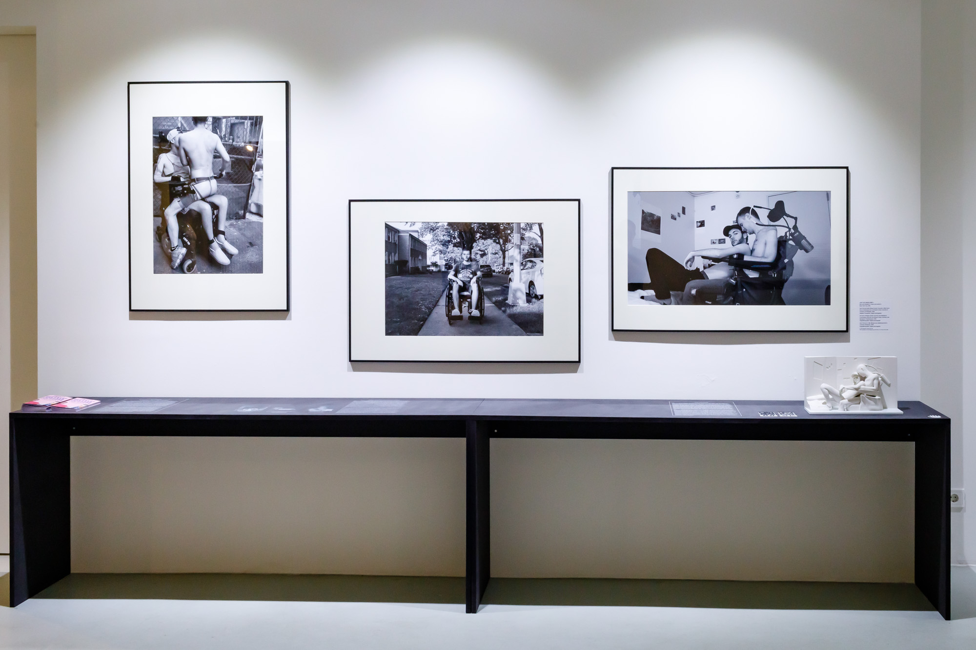 Three black and white photographs of a man in his wheelchair in states of embrace with others