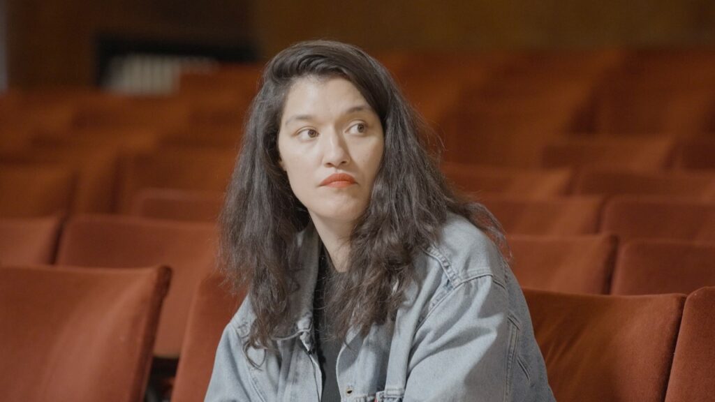 A woman with long dark hair sitting in a theatre