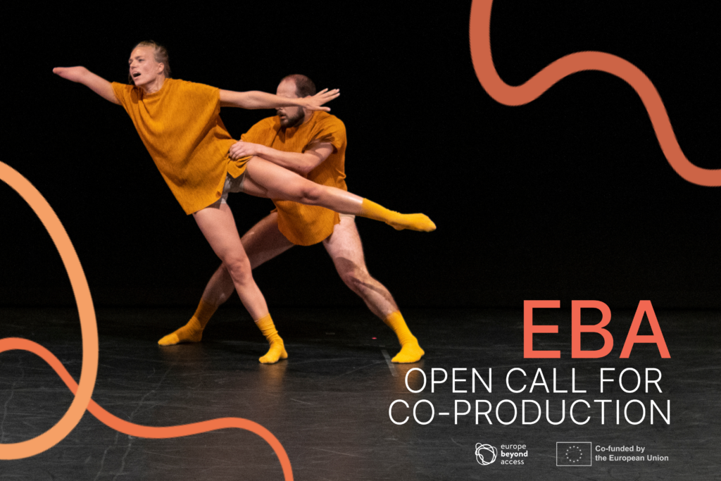 A male dancer holds a female dancer by the waist as she stretches away from him. The female dancer has one arm shorter than the other, and she reaches away in an off-balance position.