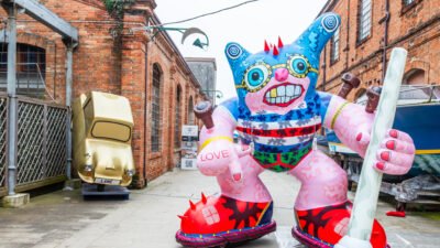 Huge inflatable sculpture and a gold car propped up in a Venice street